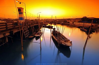 Sailboats moored at harbor against sky during sunset