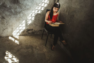 Woman sitting on chair reading book