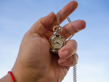 Close-up of hand holding ring against sky