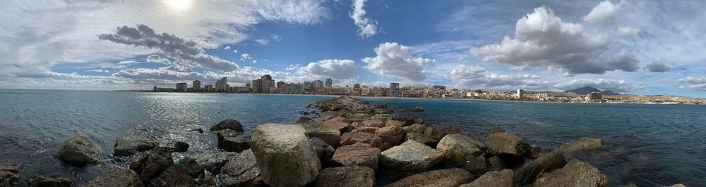 Panoramic view of sea by city against sky