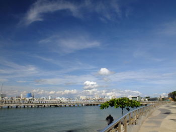 Bridge over sea by city against sky