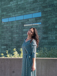 Young woman standing against brick wall