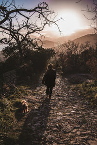 Rear view of man walking with dog against sky