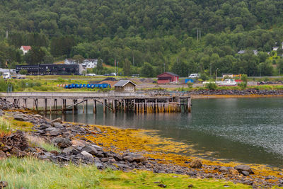 Wooden pier on the beach with houses and mountains in the background