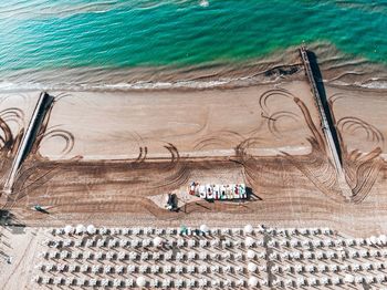 High angle view of lounge chairs and pier art beach on sunny day