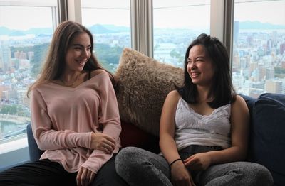 Sisters talking while siting on sofa at home