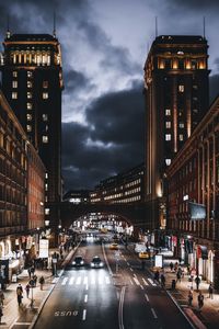 Vehicles on road amidst buildings in city at night