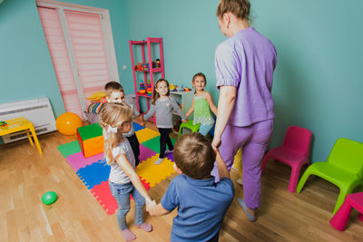 Rear view of people playing with umbrella on floor