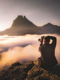 Man photographing on mountain against sky