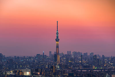 Illuminated cityscape against sky during sunset