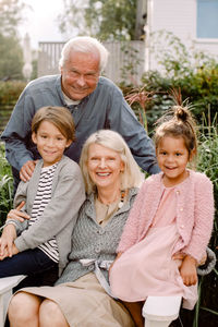 Portrait of grandparents and grandchildren sitting in backyard