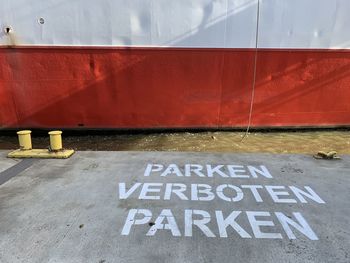 High angle view of sign on footpath against wall