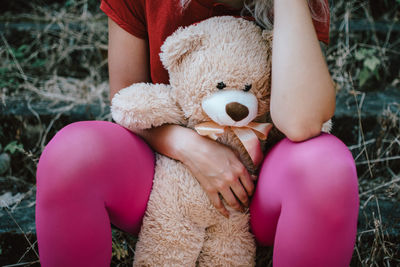 A young girl holding her teddy bear in pink socks