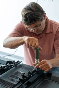 Man installing the wall base for the television, it is a smart tv, adjusting with screwdriver