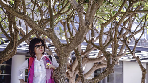 Portrait of young woman standing against plants