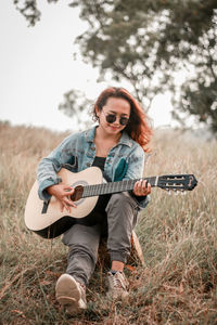 Full length of man playing guitar on field