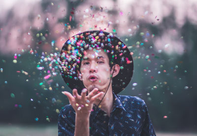 Portrait of young man blowing confetti