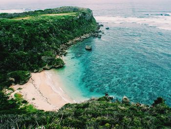 Scenic view of overgrown cliff by sea at okinawa island