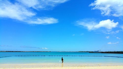 Man at beach against blue sky