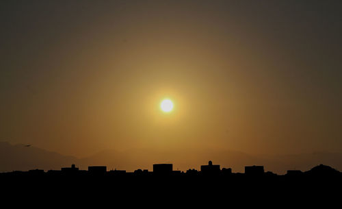 Silhouette buildings against sky during sunset