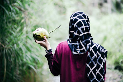 Rear view of woman holding coconut