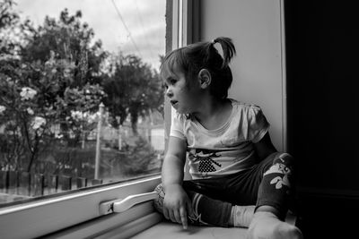 Girl looking through window at home