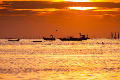 Silhouette boats sailing in sea against sky during sunset