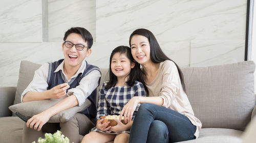 Happy family watching tv while sitting on sofa