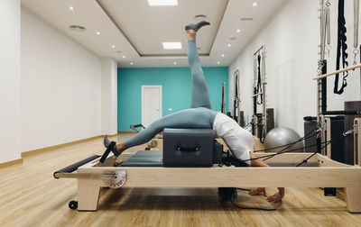 Flexible woman exercising on reformer machine in studio