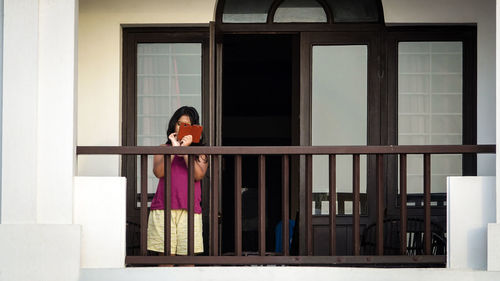 Portrait of woman standing against window