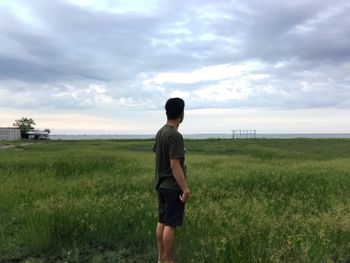 Rear view of man standing on field against sky