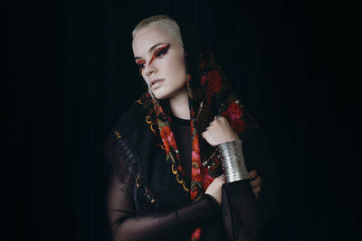 Portrait of beautiful woman standing against black background