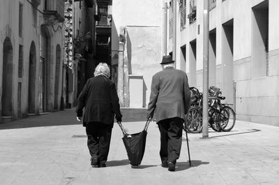 Rear view of people walking on road in city