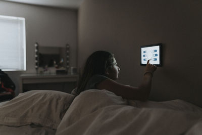 Girl adjusting temperature of bedroom through digital tablet at modern home