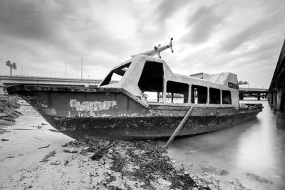 Abandoned boat moored at beach against sky