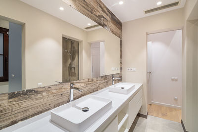 Modern tiled bathroom with a shower area, two sinks and a big wall mirror.