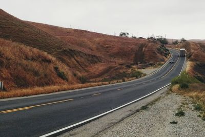 Road passing through landscape against clear sky