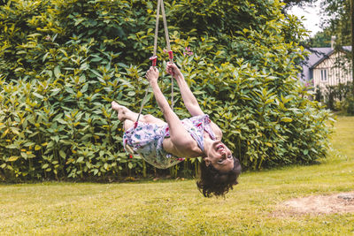Pretty middle aged dark haired woman swinging on childrens swings in a french park