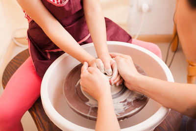 Mother teaching daughter potters wheel