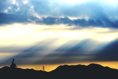 Silhouette of mountain against cloudy sky at sunset