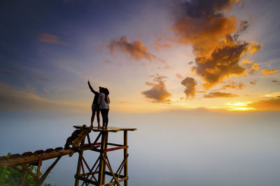 Silhouette man standing by sea against sky during sunset