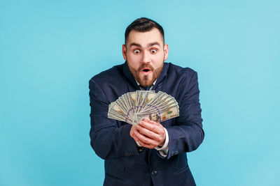 Happy man looking at dollars against blue background