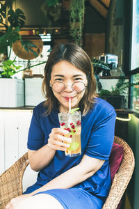 Portrait of smiling woman holding drink in restaurant