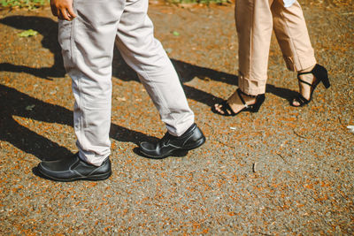 Low section of people walking on autumn leaves