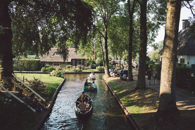 Rear view of people on boats sailing in canal by trees