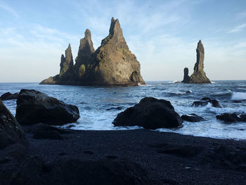 Rock formation on beach against sky