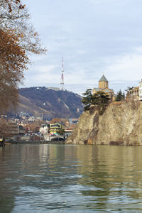 Buildings by river against sky