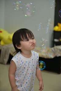 Cute girl blowing bubbles at home