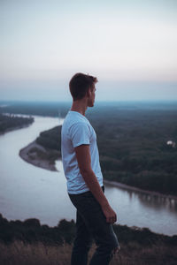 Young man looking at sea against sky