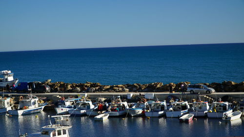 Boats in sea against clear blue sky